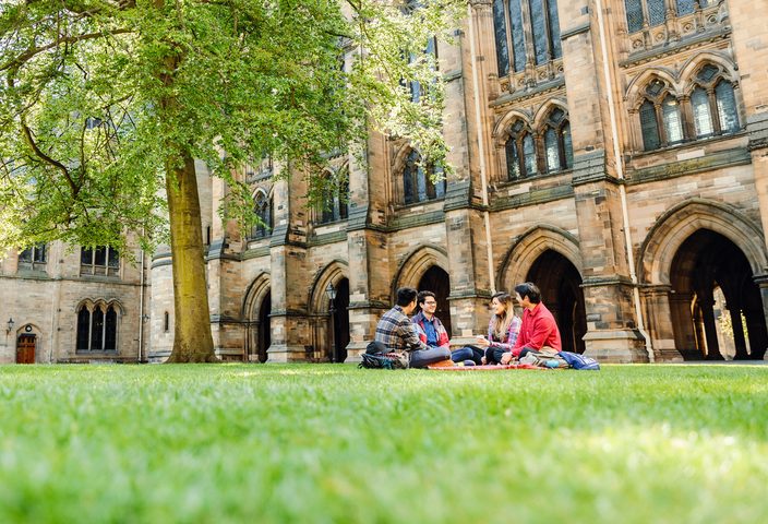 A group of students sitting on grass at campus yard