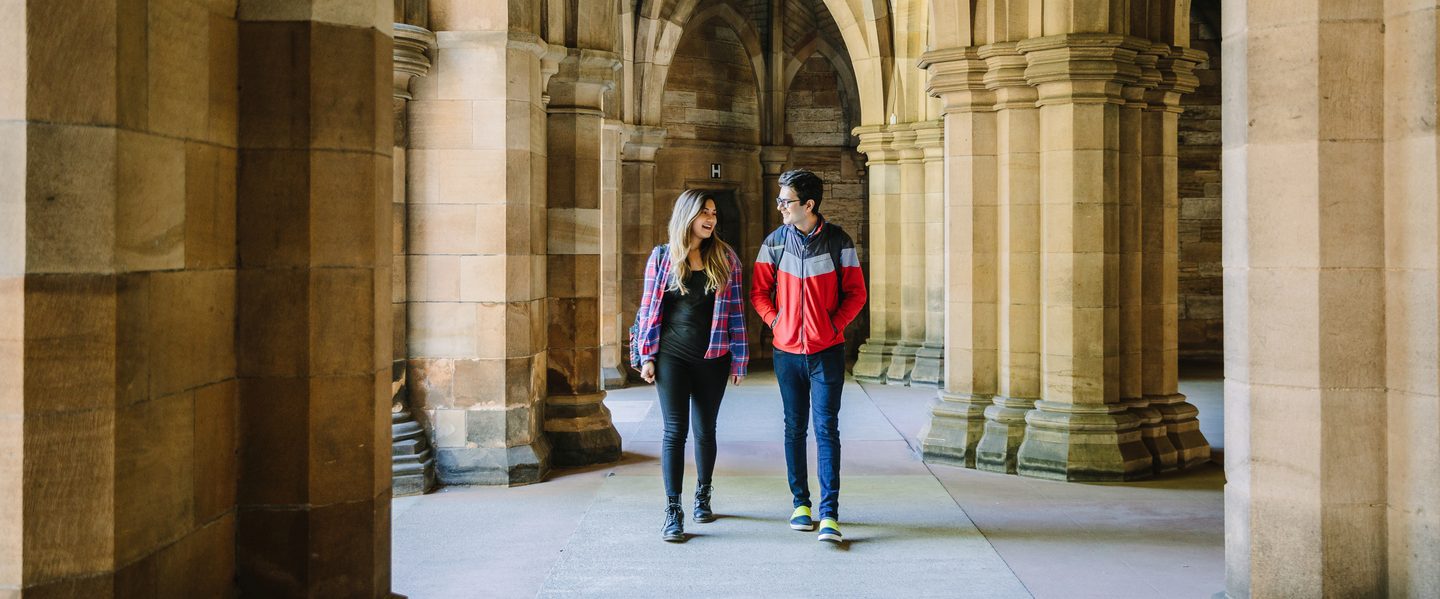 Students walking inside the Gilbert Scott building and talking