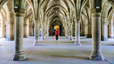 A student walking inside the Gilbert Scott Building