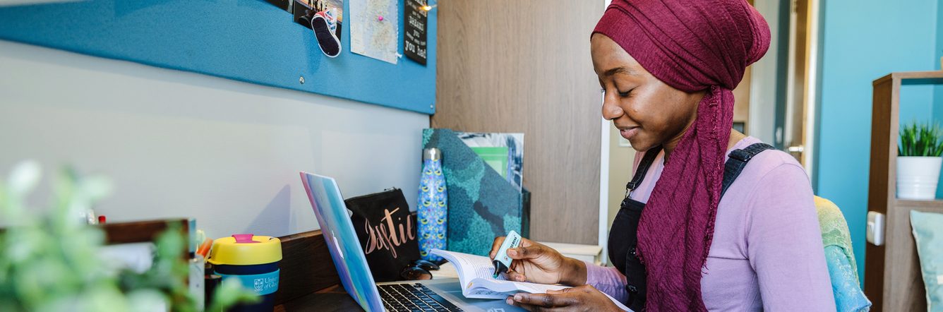 Student studying on her book with her laptop open