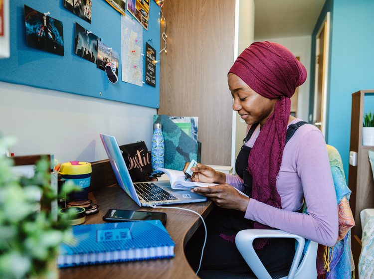 Student studying on her book with her laptop open