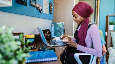 Student studying on her book with her laptop open