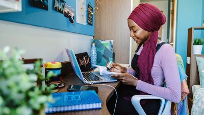 Student studying on her book with her laptop open