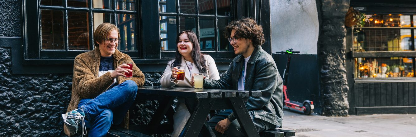 students sitting on a bench, having beverages and enjoying the weather outside