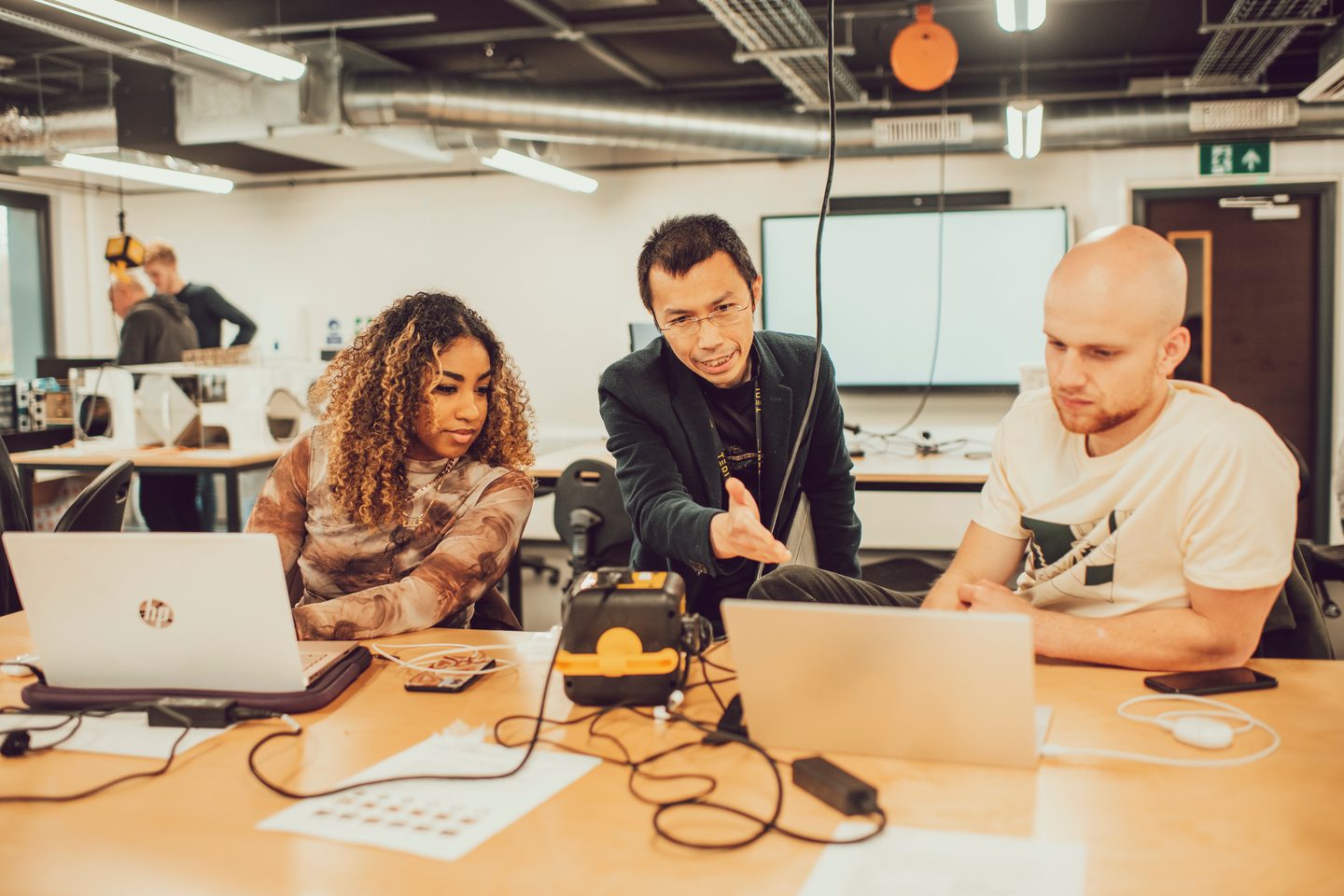 students and teacher working on laptops in classroom