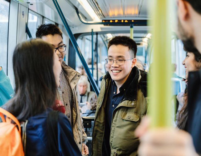 Students standing in the tram and smiling to each other