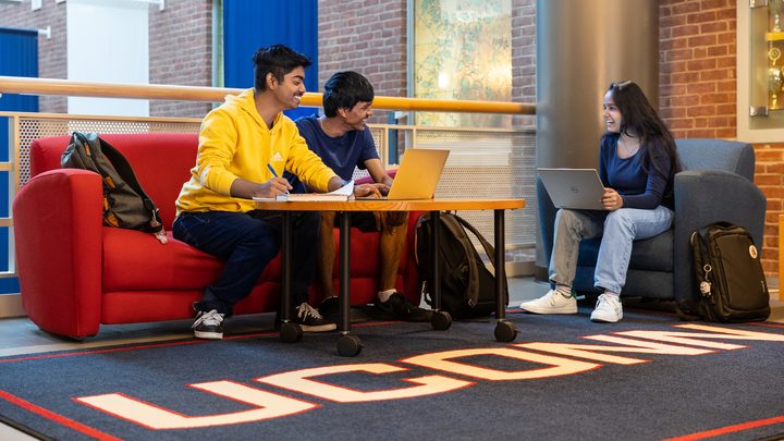 Three UCONN students studying and laughing in a Storrs building