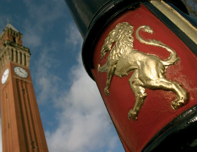 University seal on lamppost with Old Joe Clock in the background