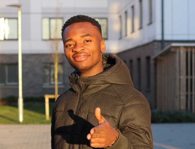 Kayode is posing for picture on campus