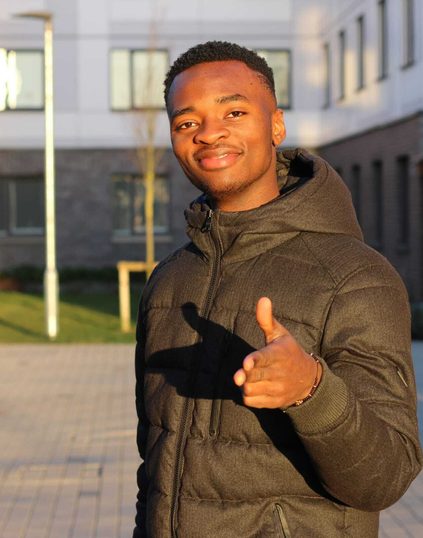 Kayode is posing for picture on campus