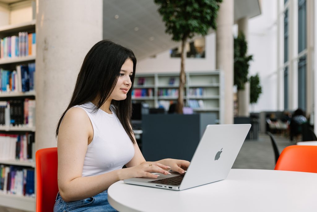 A BUINTCOL student on her laptop in the library