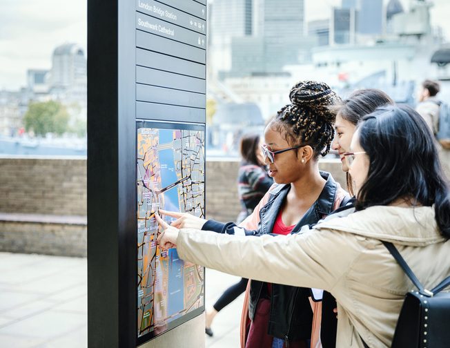 Three students looking at city map on the board