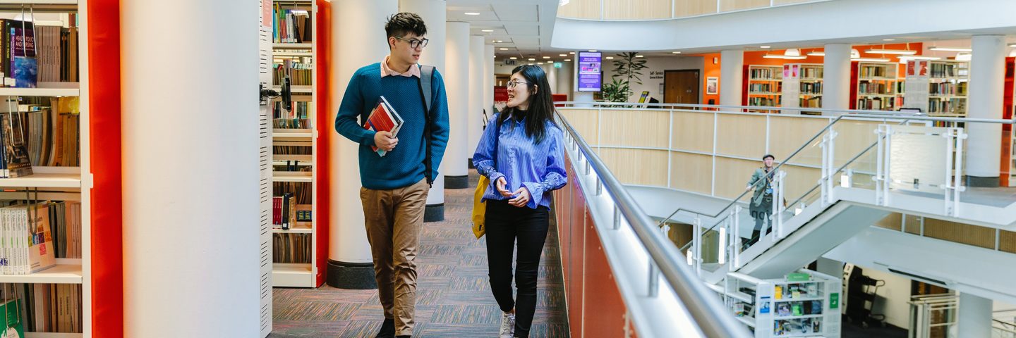 Two NTIC students walking in the library