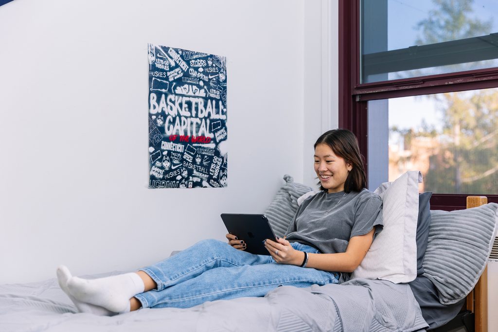 A UCONN student relaxing on her bed with a tablet