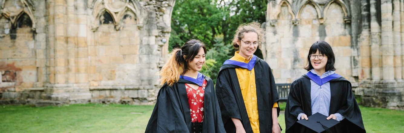 Three students out and about wearing graduation robes