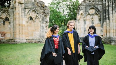 Three students out and about wearing graduation robes