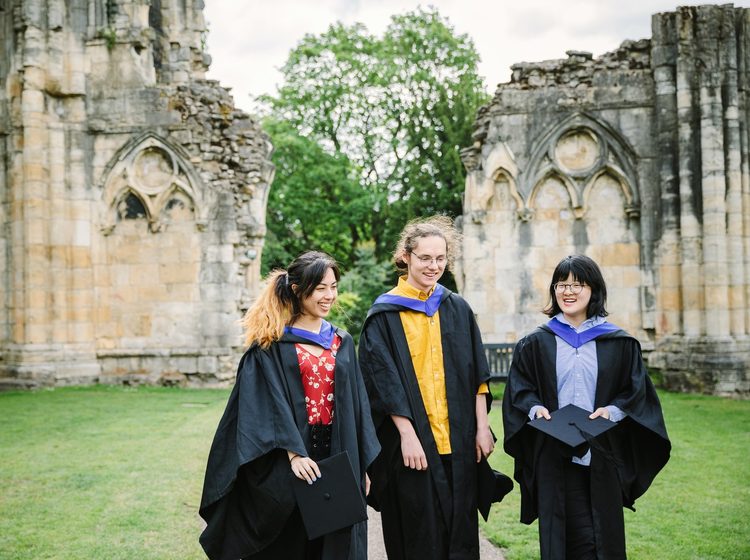 Three students out and about wearing graduation robes