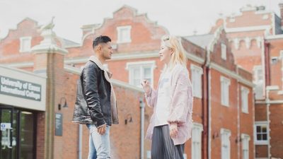 A young, dark-haired male student talking to a young, blond-haired student outside the University of Essex International College