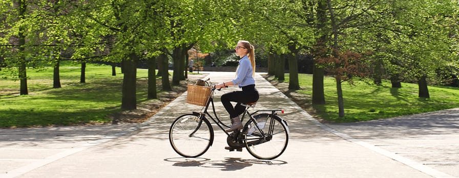 A young woman cycles through a park