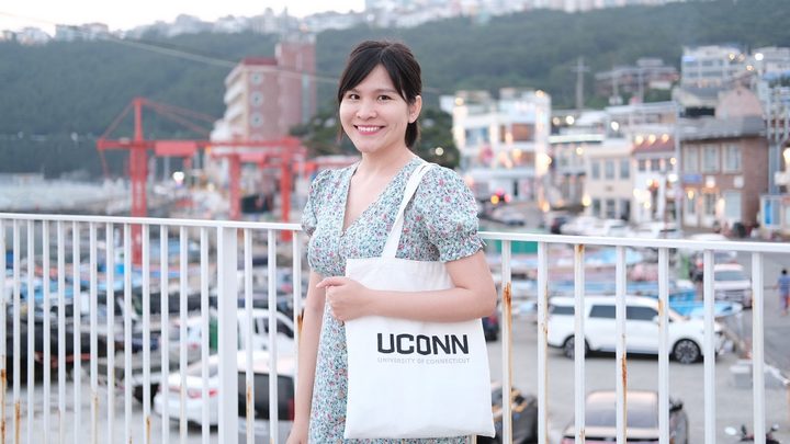 Tam Phan posing with a UConn tote bag