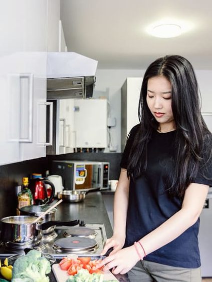 student slicing tomatoes in kitchen