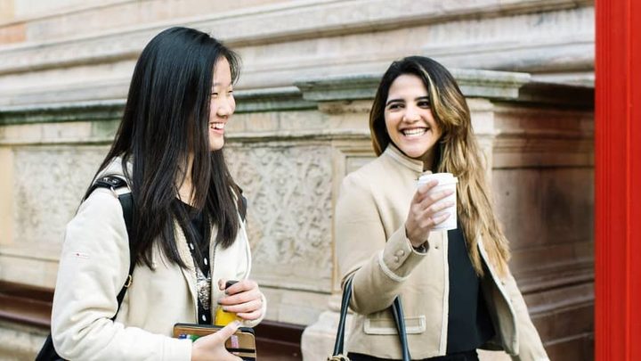 Two students walk through London talking and laughing