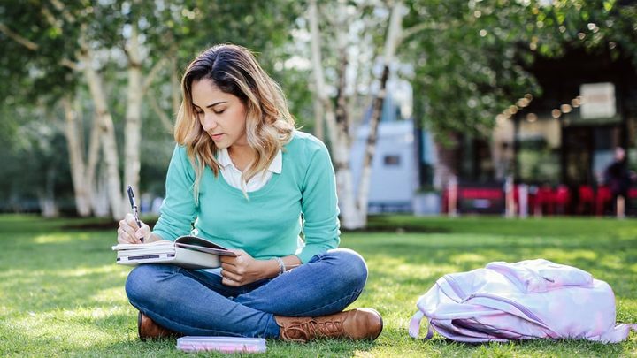 student writing in her book in the park