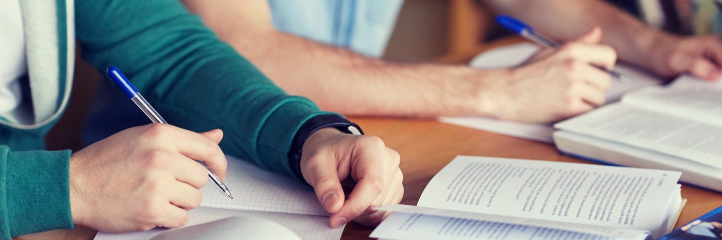 Close up of hands writing on a book