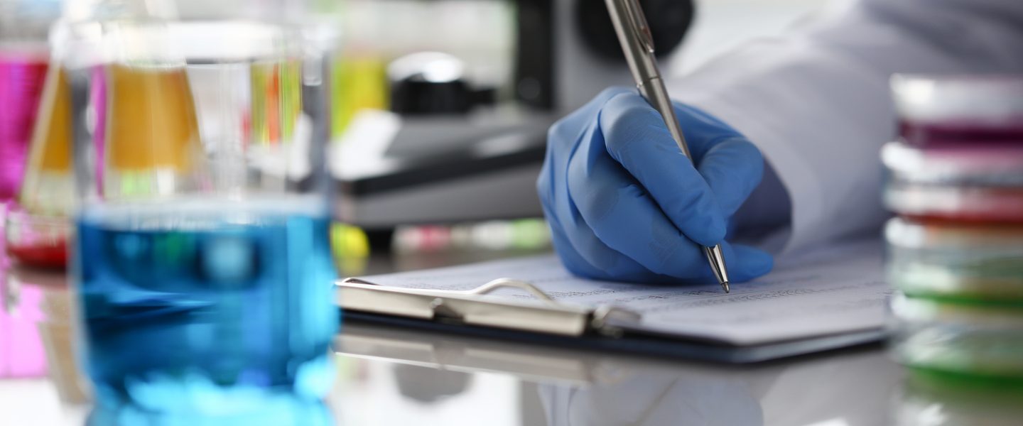 Close up of researcher writing result of chemical analysis