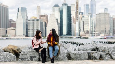 Students sitting on the rocks by the sea side in New York