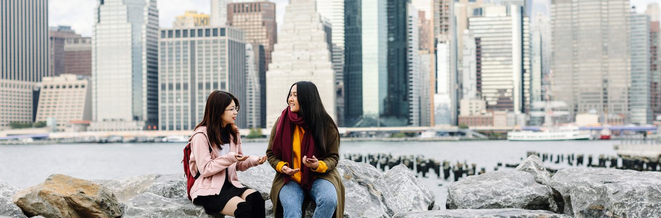 Students sitting on the rocks by the sea side in New York