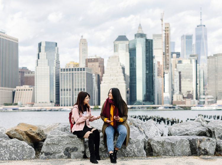 Students sitting on the rocks by the sea side in New York