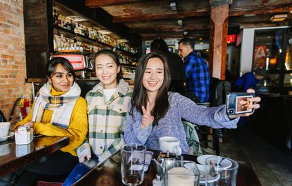 Pace University students taking a group selfie at a restaurant