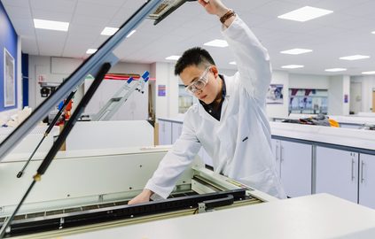 Science student wearing safety gear while operating equipment