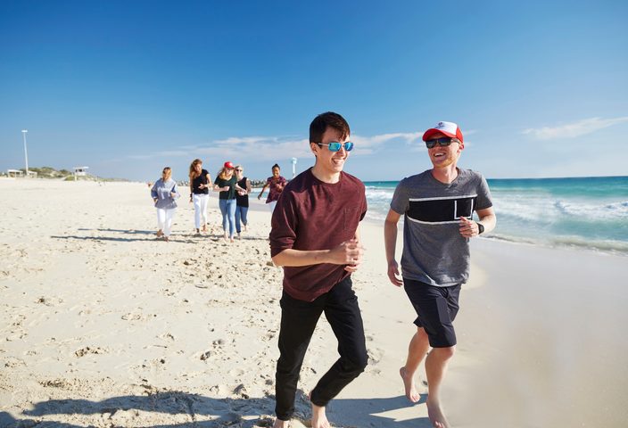 Group of students playfully jogging on the beach