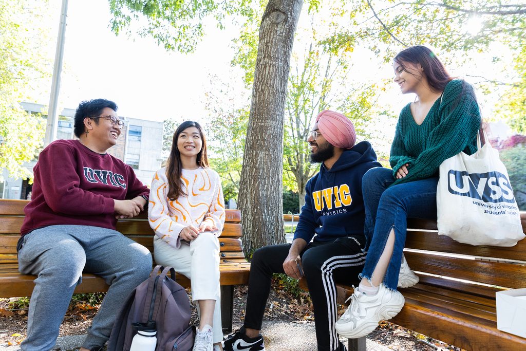 UVic students chatting and sitting on a bench