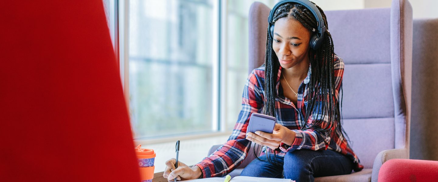 Student completing her work on campus while listening to music