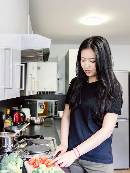 student slicing tomatoes in student accommodation kitchen