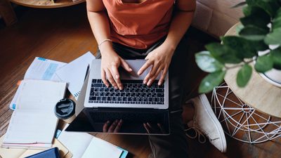 Close up of girl sitting on floor working on laptop