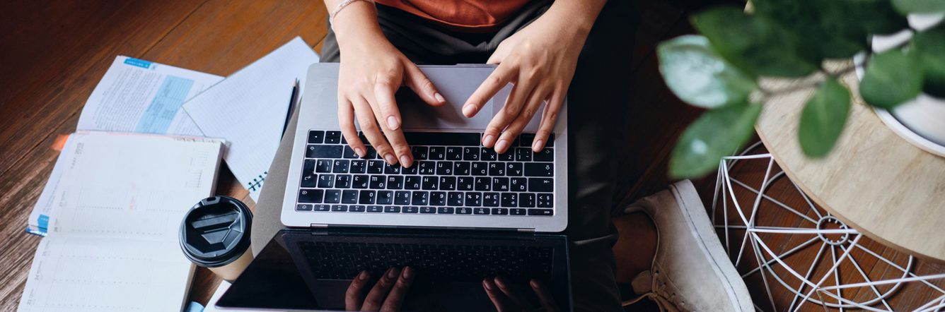 Close up of girl sitting on floor working on laptop