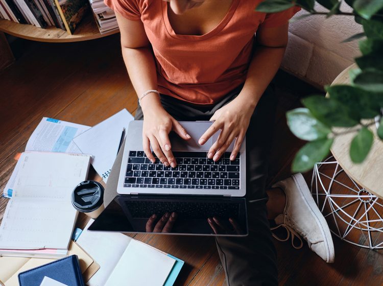 Close up of girl sitting on floor working on laptop