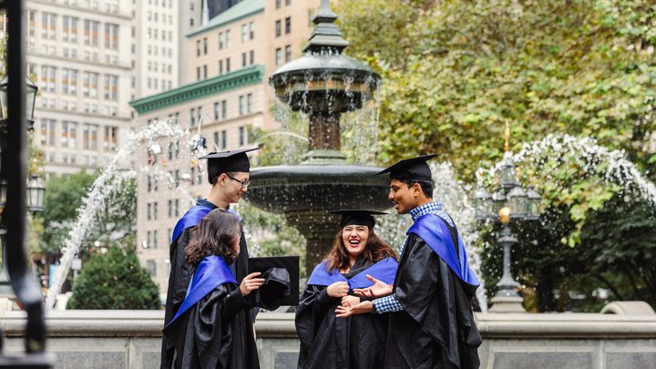 Pace university students socialising by the fountain in their graduation robes