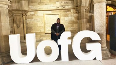 David posing with the University of Glasgow sign