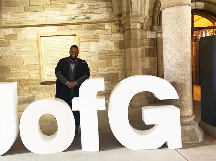 David posing with the University of Glasgow sign