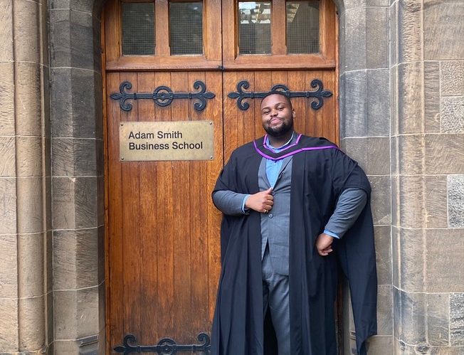 David posing in front of campus building's door