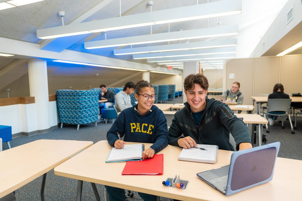 Two pace university students looking at a laptop