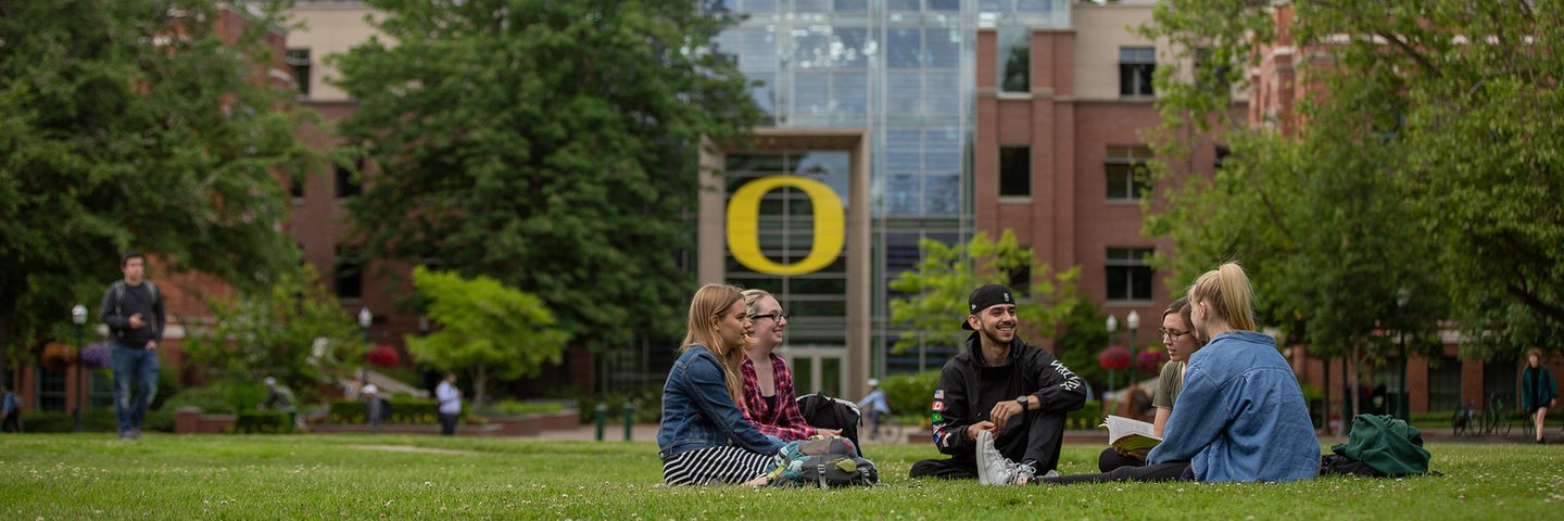 Five UO students sitting down on the campus green park socialising