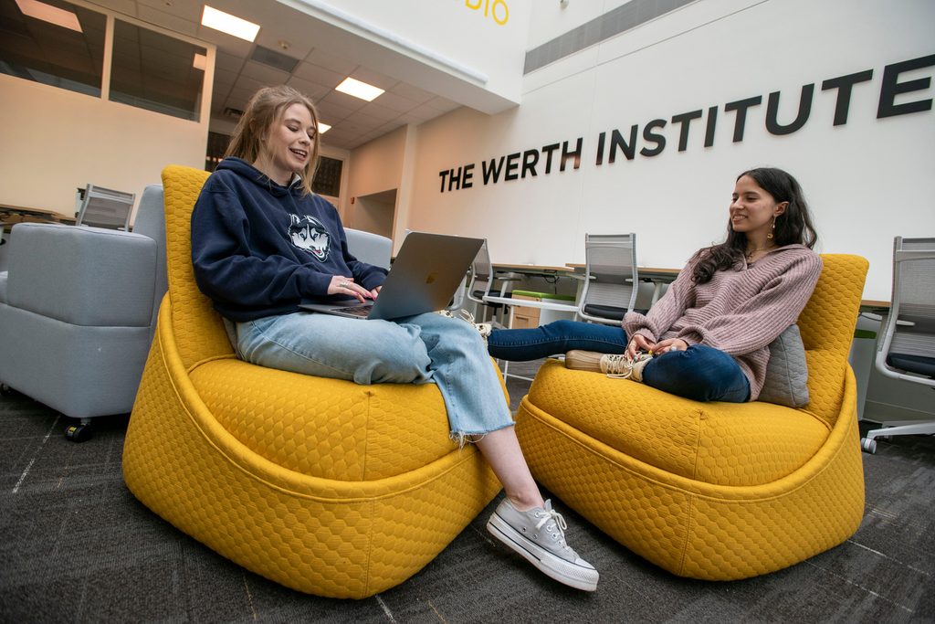Two students at the UConn Institute sitting on yellow bean bags chatting