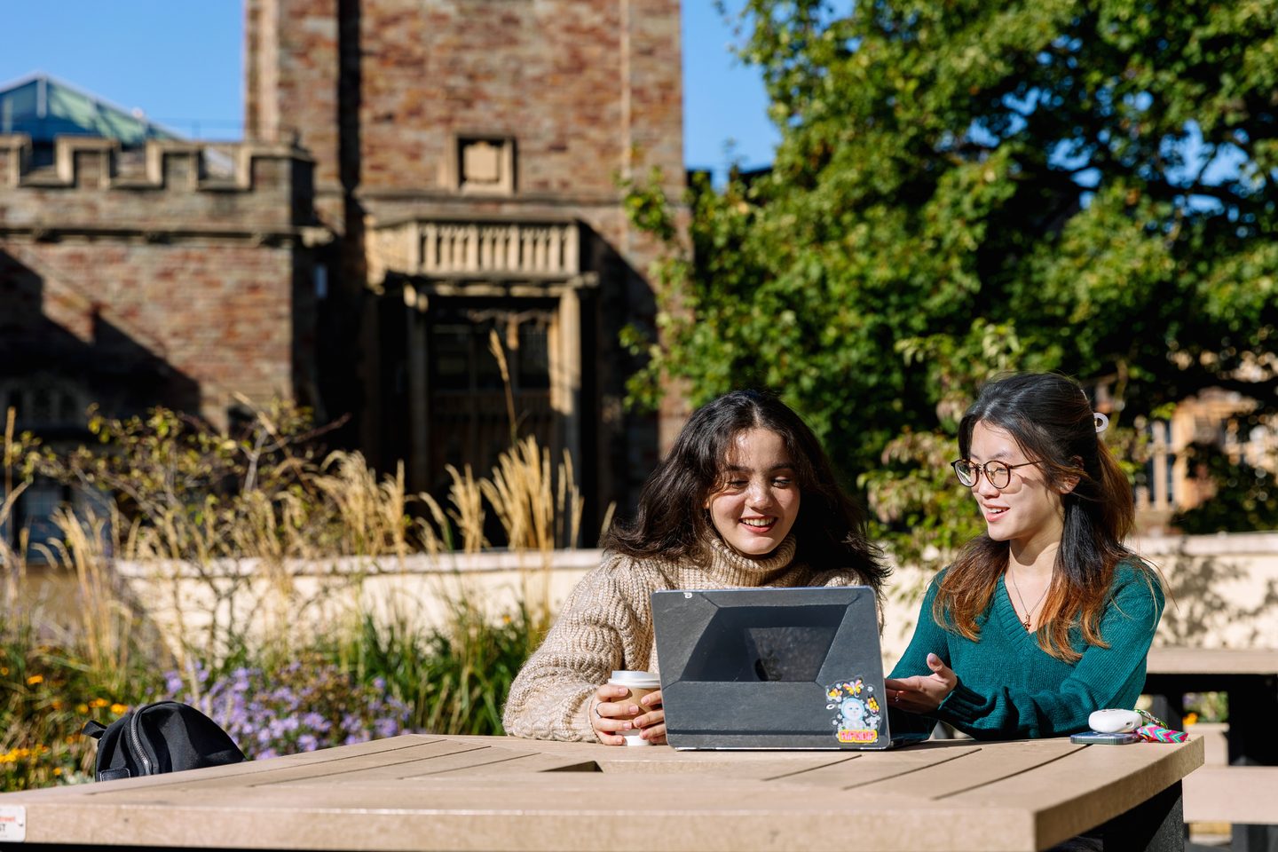 Two students outdoors looking at their laptop