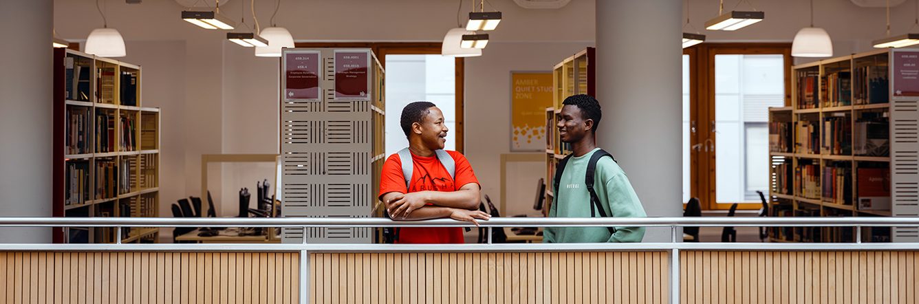 Two students talking in a university library